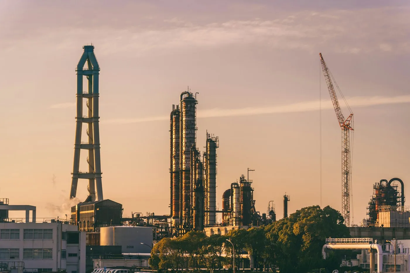 Refinery towers silhouetted against a vivid orange sky